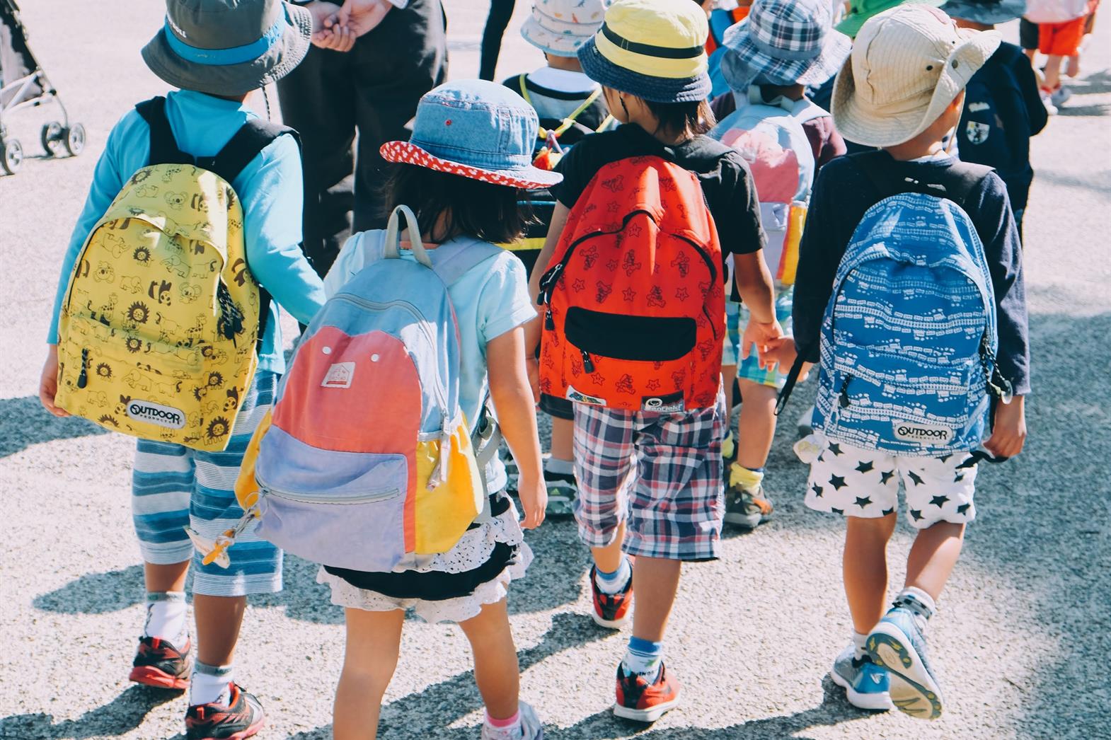 Group of children wearing backpacks walking away