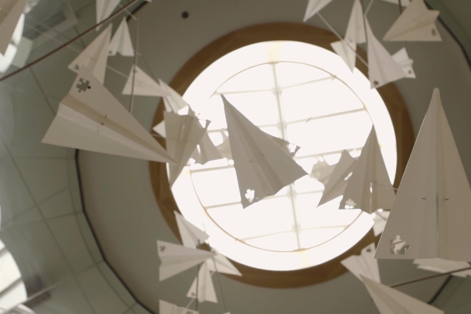 several paper airplanes floating in front of a round window. 