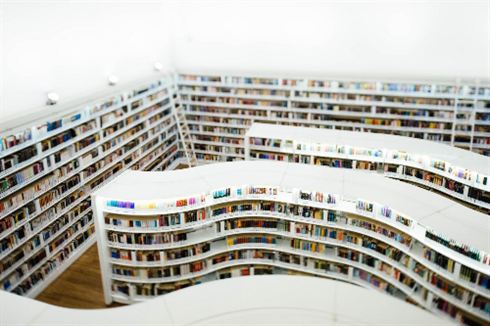 a library with white shelves and many books. 