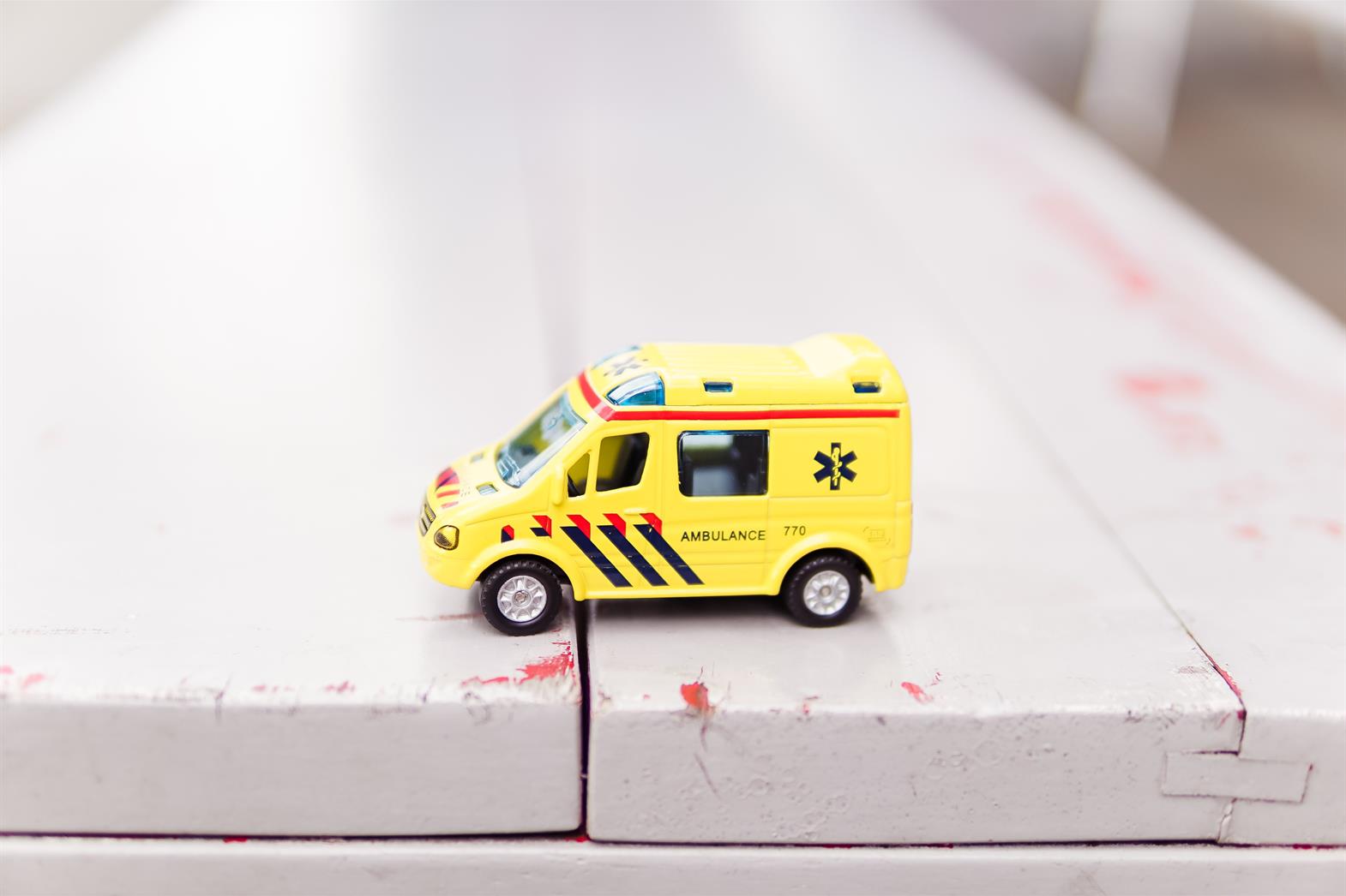 Toy ambulance sitting on a wooden bench