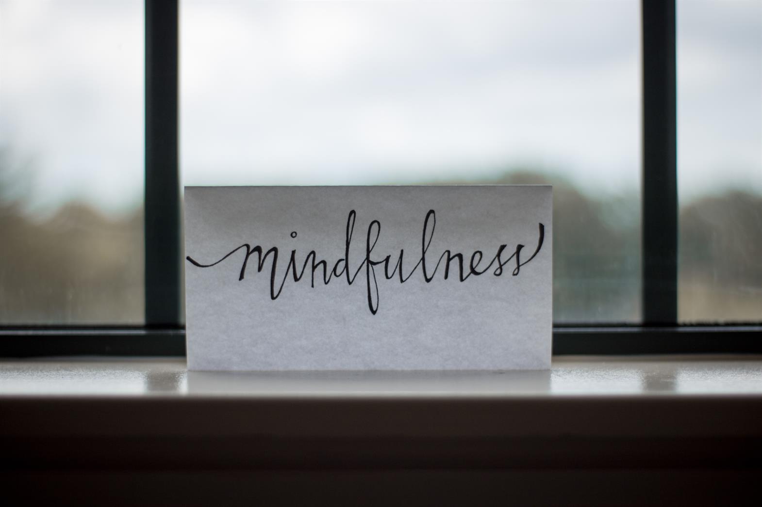 The word mindfulness written on a piece of paper propped  in front of a window
