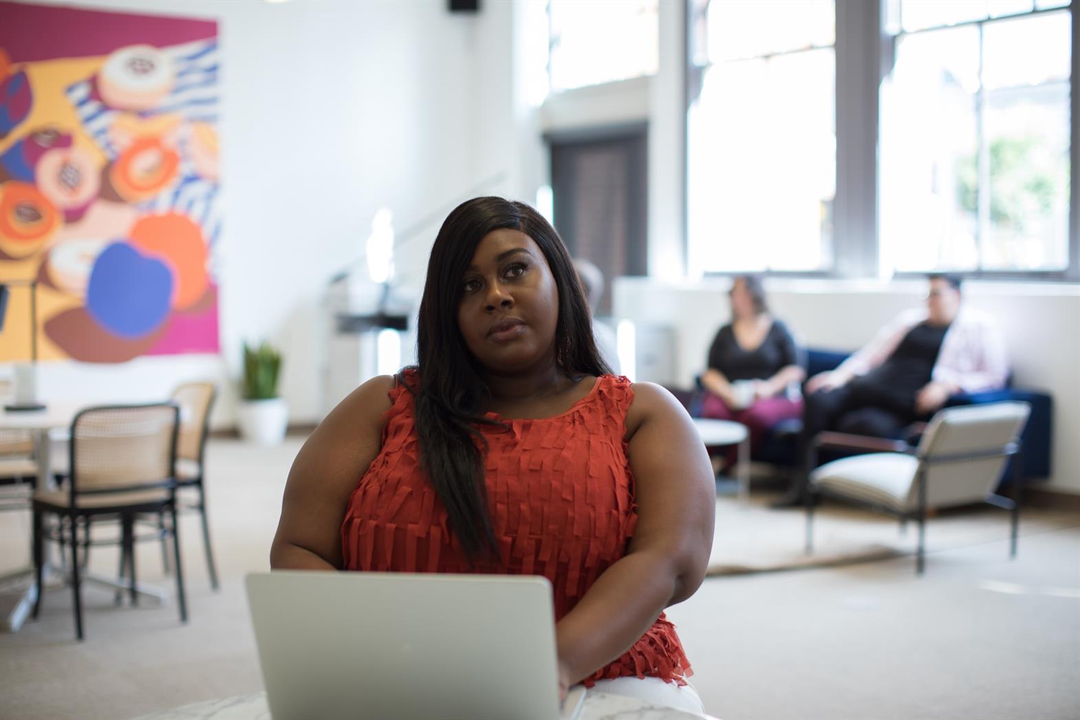Woman of colour sitting at a compute looking thoughtful