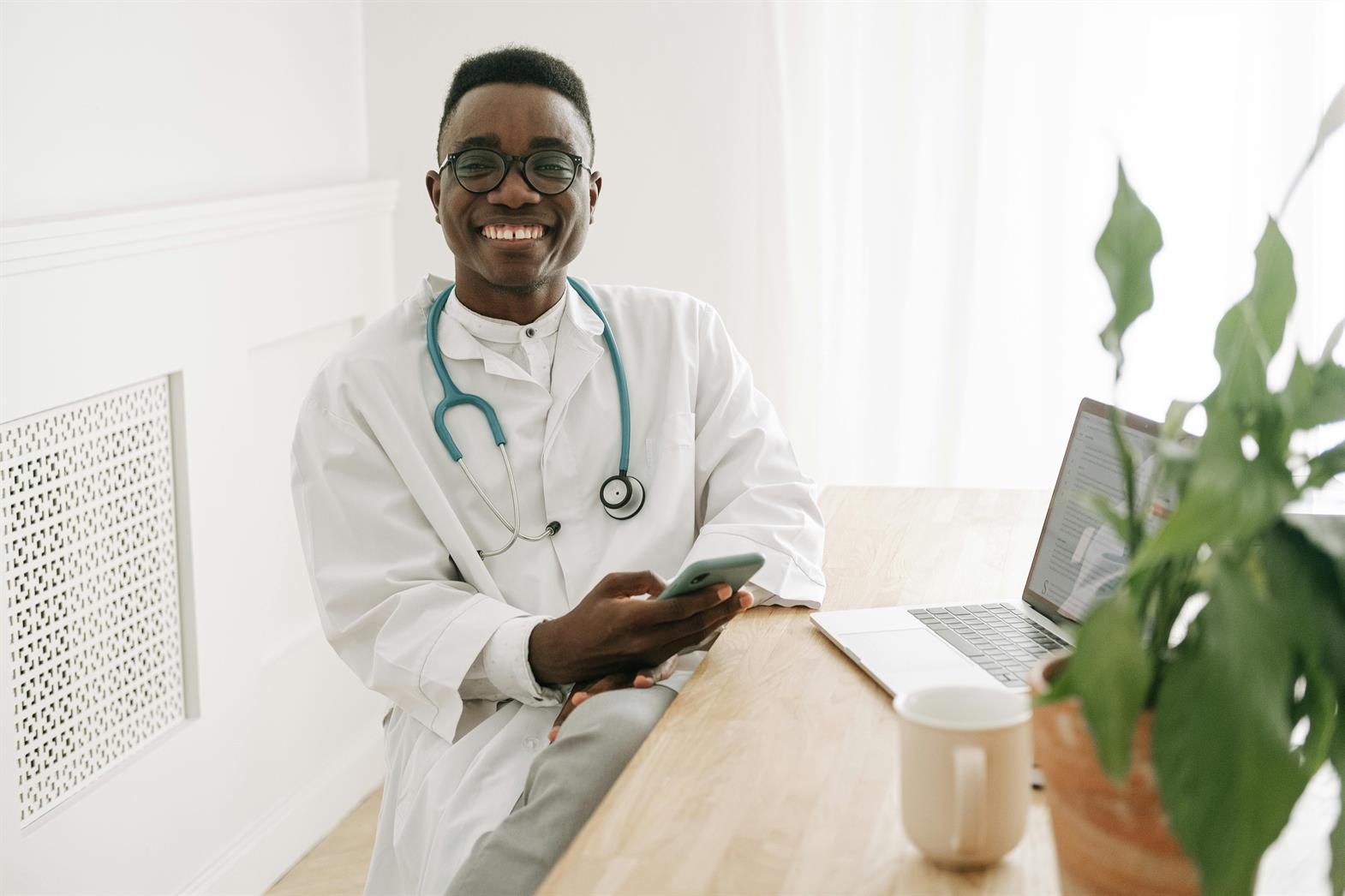 Un médecin souriant tenant un smartphone