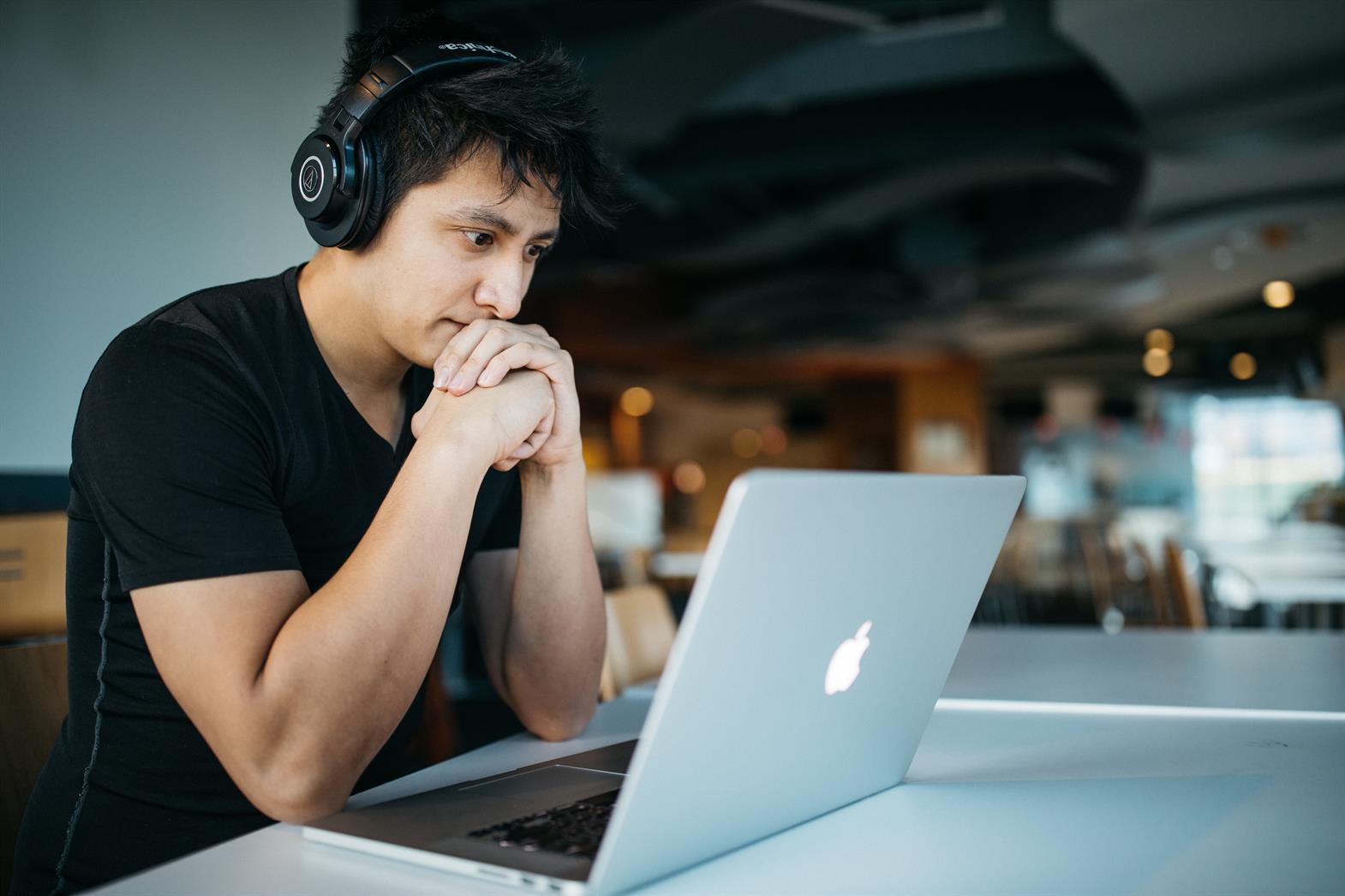 Young man wearing headphones looking at a laptop