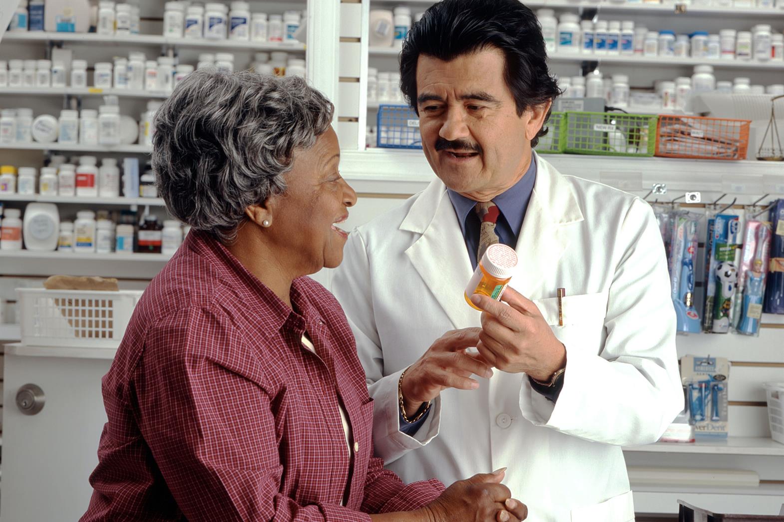 Pharmacien parlant à une femme âgée au sujet d’un médicament dans une bouteille.