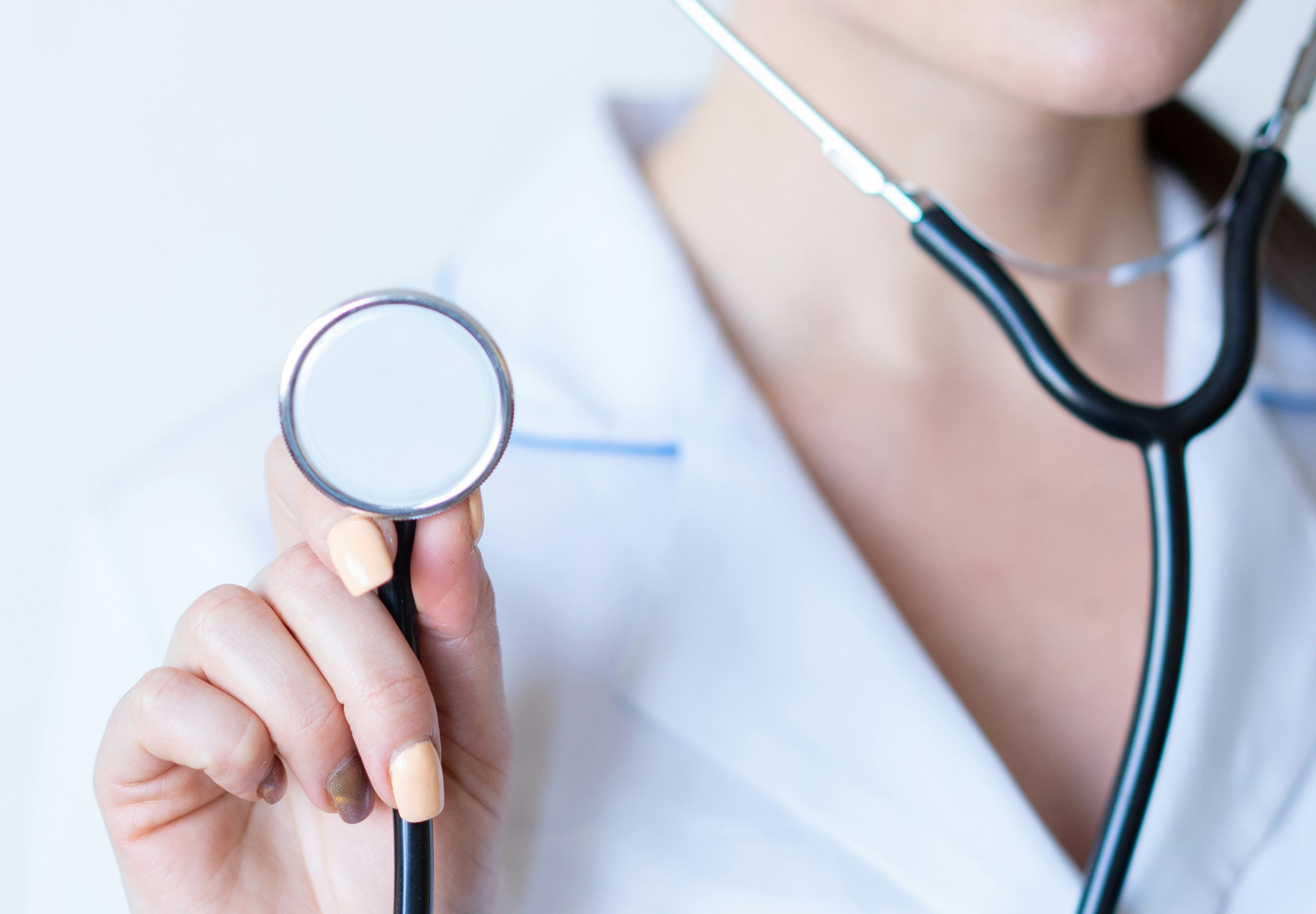 a female doctor in a white lab coat holding a stethoscope